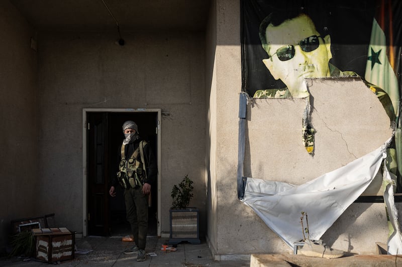 A rebel fighter walks past a defaced picture of toppled Syrian president Bashar al-Assad in a military base in Damascus 2024. Photograph: Sameer Al-Doumy/AFP via Getty Images
