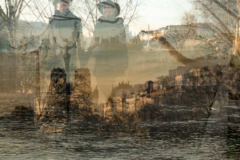 A double exposure image shows two people in hats standing by water, overlaid with a cityscape featuring historic buildings, trees, and reflections on the water, creating a dreamy, layered effect.