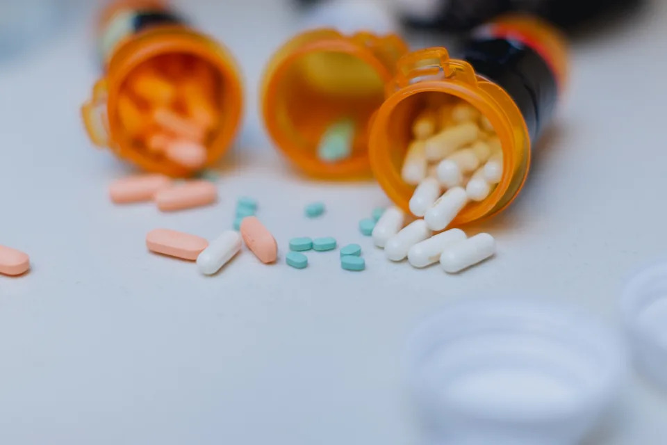 Pills spilling from orange prescription bottles onto a surface