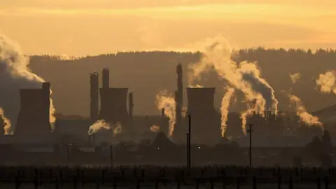 Getty Images A general view of the Grangemouth refinery during a sunset, an orange-tinged sky and the smoke coming from giant industrial towers lit up by the sun