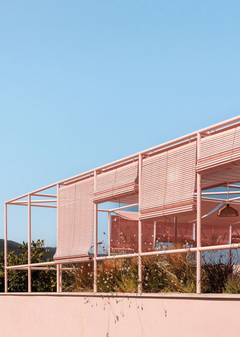 atelier RUA's light pink house contrasts with surrounding greenery in portugal