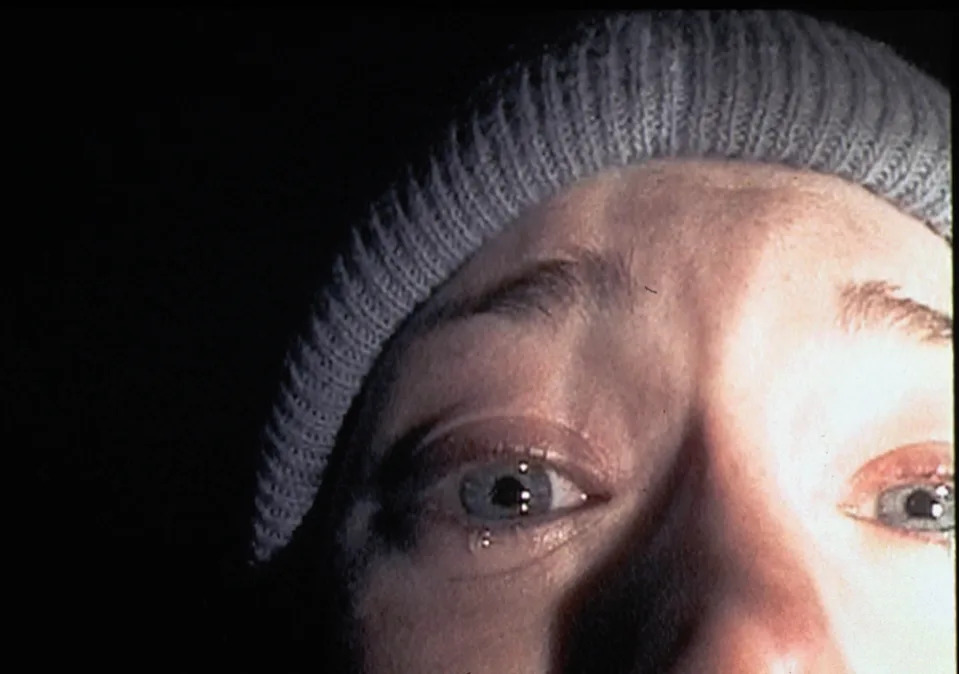 A person wearing a knit cap looks intently at the camera, eyes wide open, evoking a sense of fear or surprise