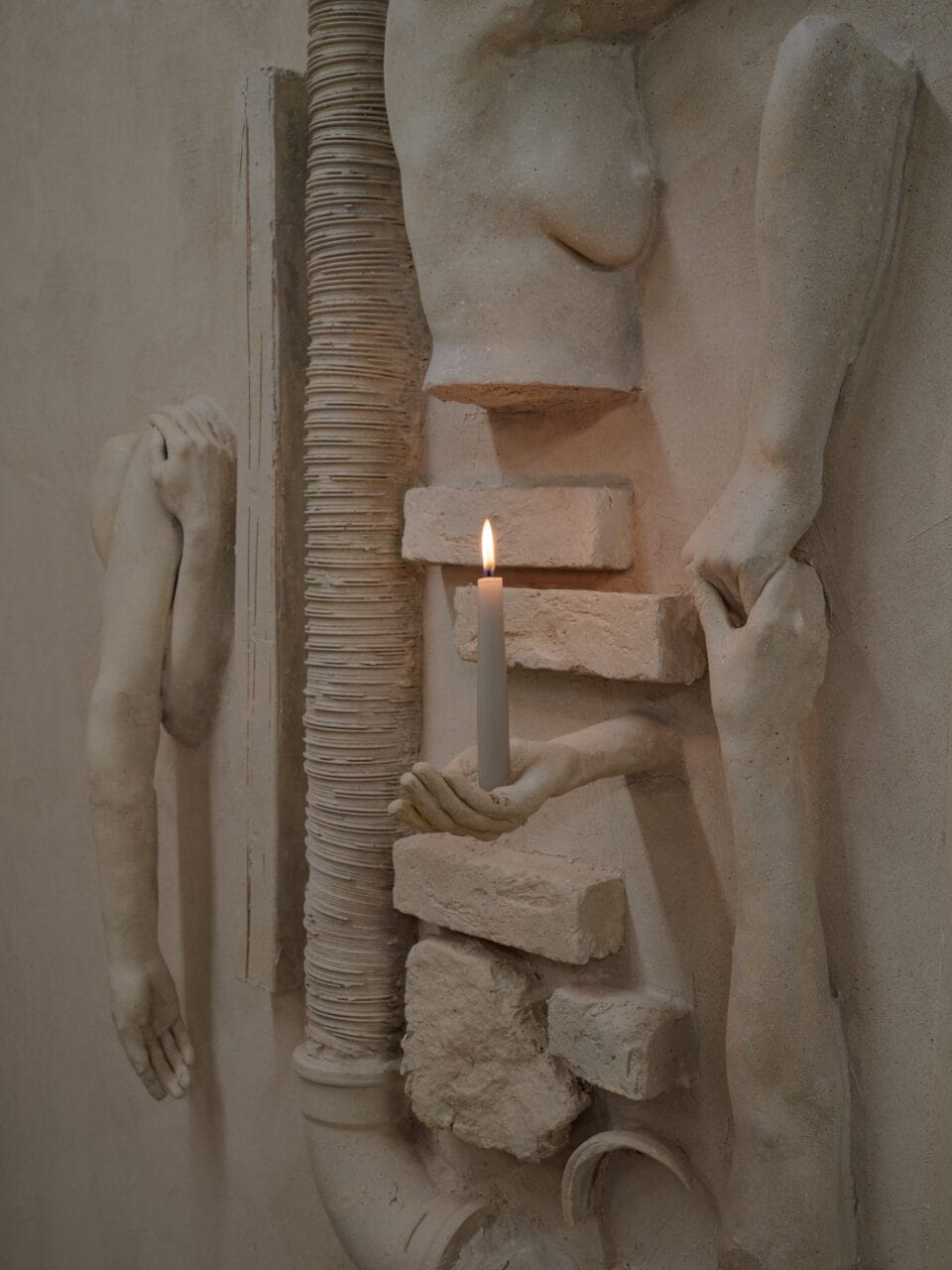 An art installation by Clementine Keith-Roach and Christopher Page of plaster-cast body parts and a candle