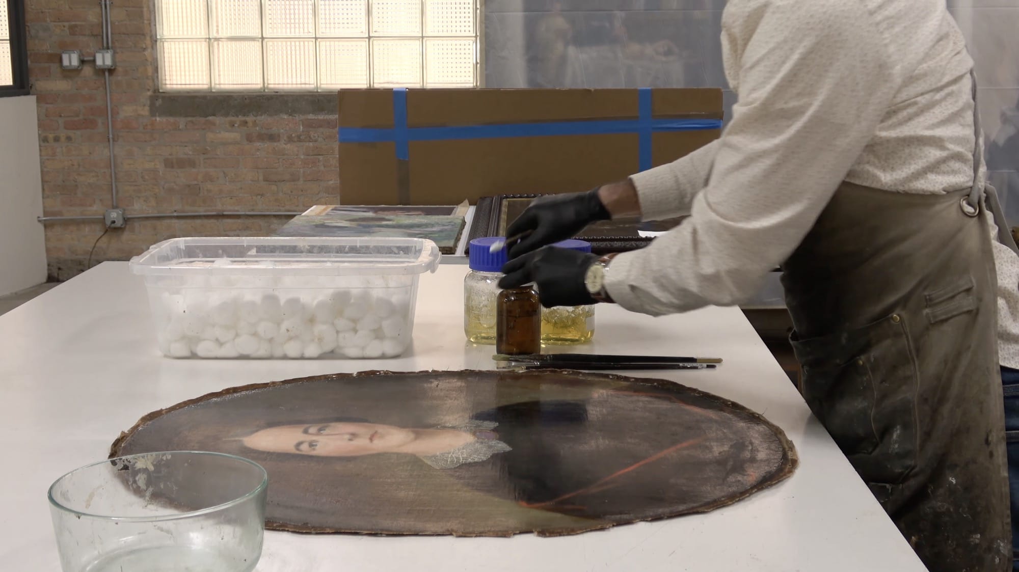 A still from a video of an oval portrait of a woman being restored