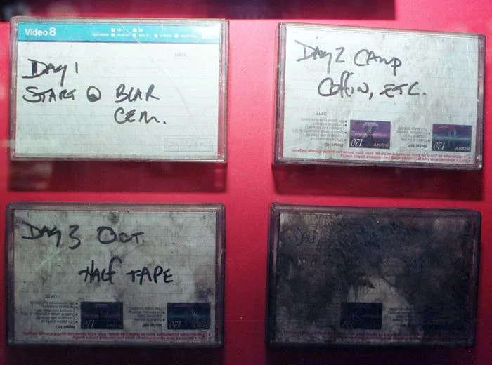 Four labeled video cassette tapes are displayed, each with handwritten notes indicating filming details and locations for a multi-day project