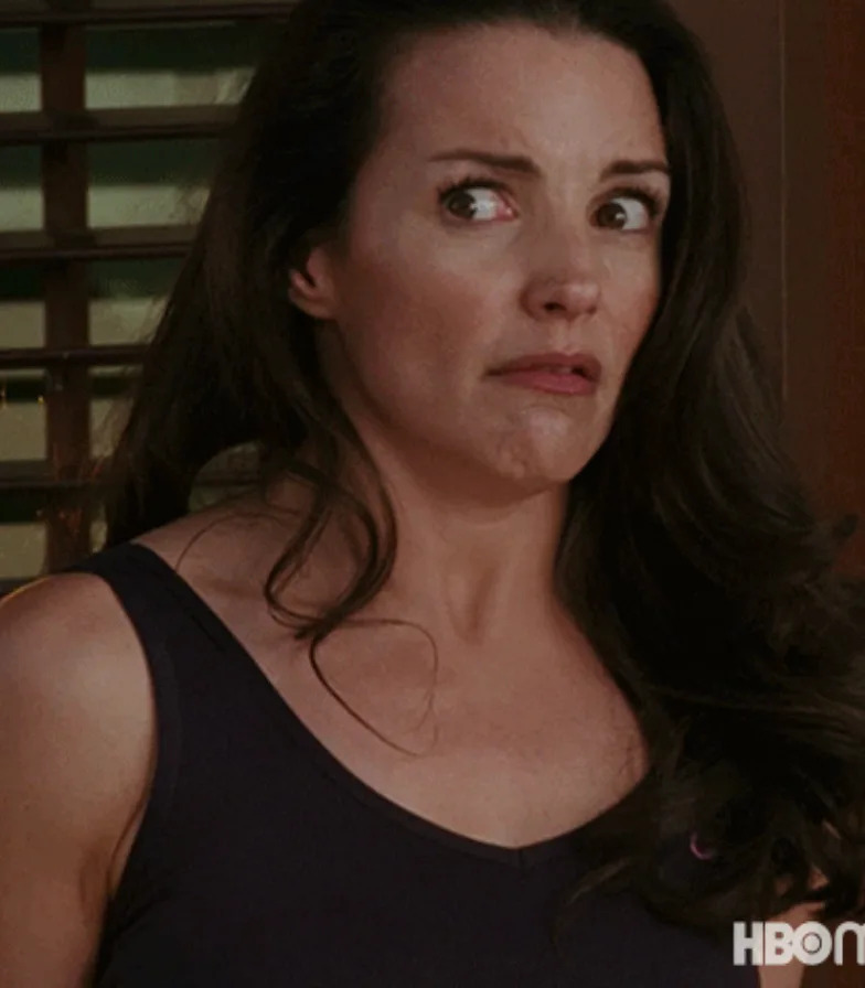 A concerned woman in a sleeveless top looks to the side with a worried expression