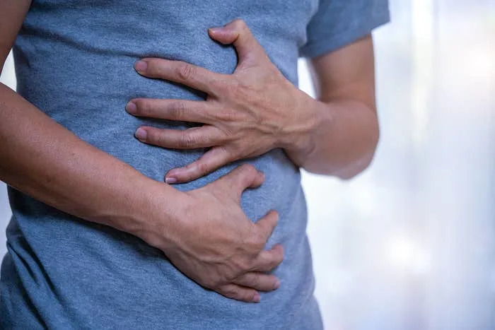 Person holding their stomach with both hands, appearing to be in discomfort or pain