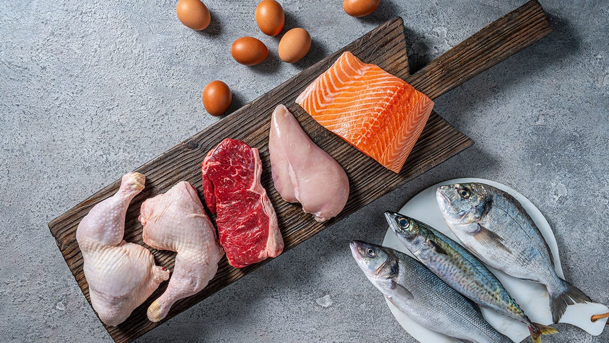 Choline-rich foods on cutting board including eggs, salmon, fish, chicken and steak.
