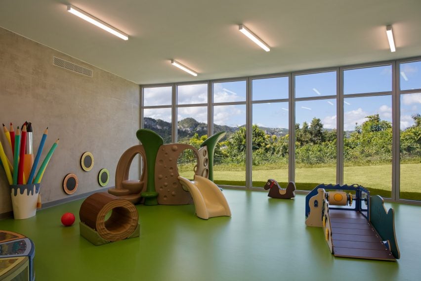 Play area with concrete walls, green flooring, and glass facade