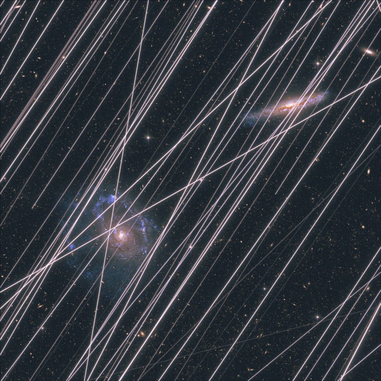 An image showing the projected contamination by satellite trails, shown as lots of diagonal white lines, passing in front of two galaxies in space