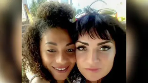 Handout A picture of Sabrina (L) and Rachel (R) smiling and looking into the camera . Sabrina has brown curly hair and Rachel has black hair with a fringe.