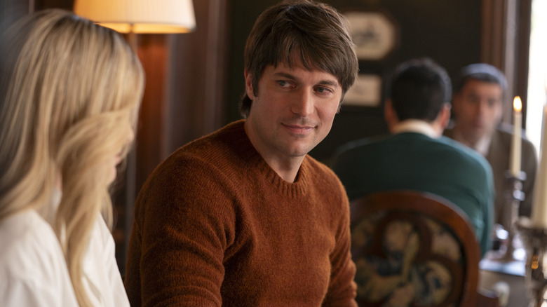 Lucas in a brown sweater talking to Camille on Emily in Paris