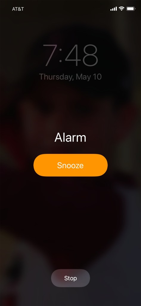 iPhone alarm screen displaying the time 7:48, "Alarm", "Snooze" and "Stop" buttons.