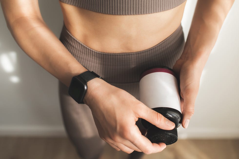 Woman holding bottle of dietary supplements or vitamins in her hands. cropped photo of females hands holding and open bottle of vitamins or protein. taking vitamins while posing over white background.