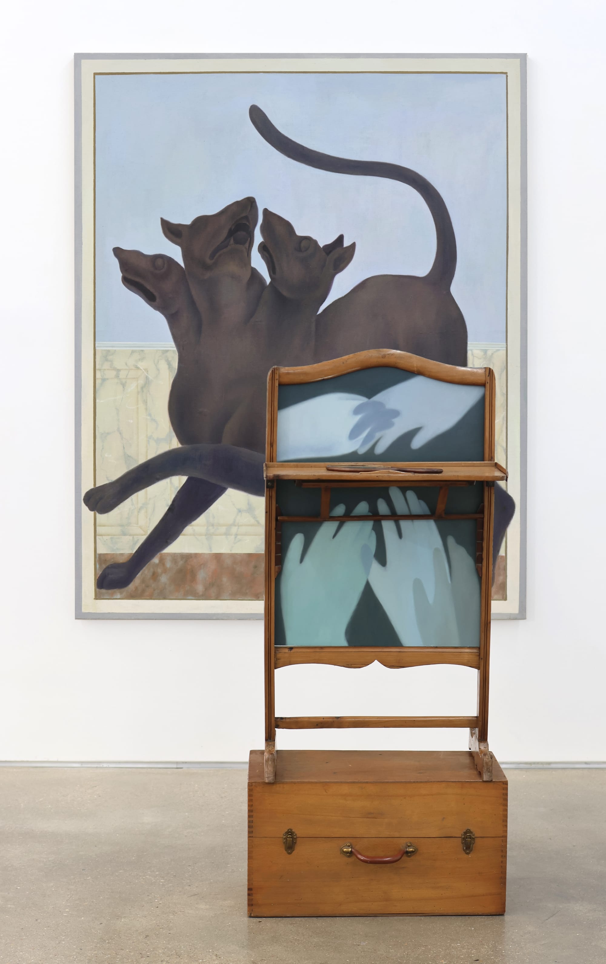 a painting and sculpture by Shuo Hao of a three headed dog and a wooden furniture piece with a painting of hands