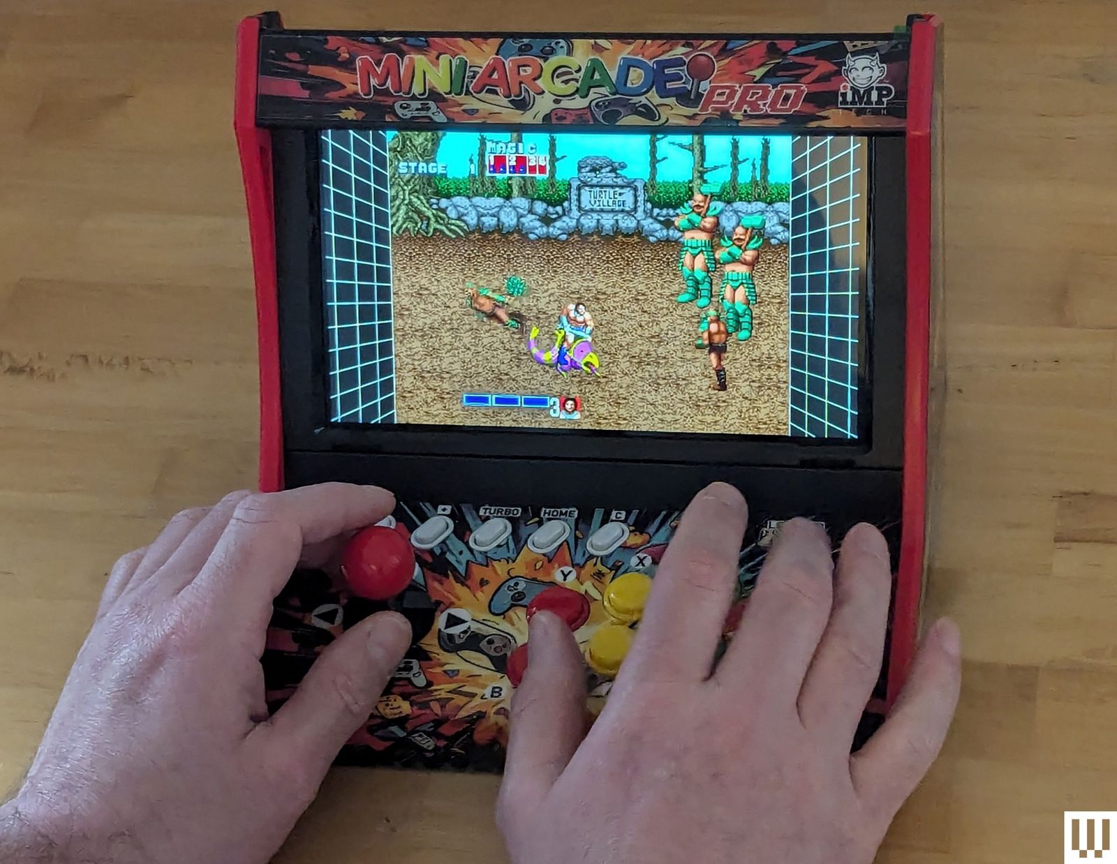 Closeup of a person's hands on the joystick and buttons of a mini tabletop arcade machine