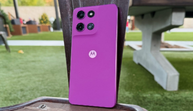 A fuschia pink phone rests on a brown chair.