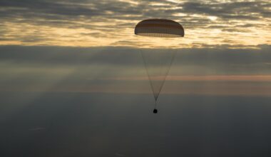 The photo features a dim horizon with the Soyuz MS-26 spacecraft as it lands by parachute.