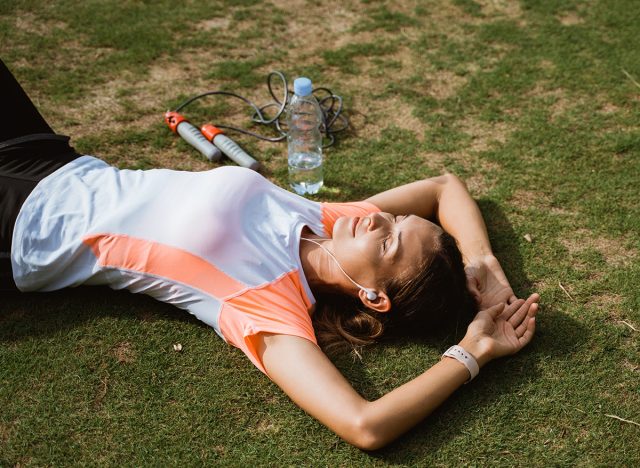 Fitness sport girl resting after intensive run, young attractive runner taking break after jogging outdoors