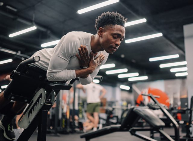 Concentrated african american sportsman doing hyperextension exercise to strengthen lower back muscles in modern fitness club