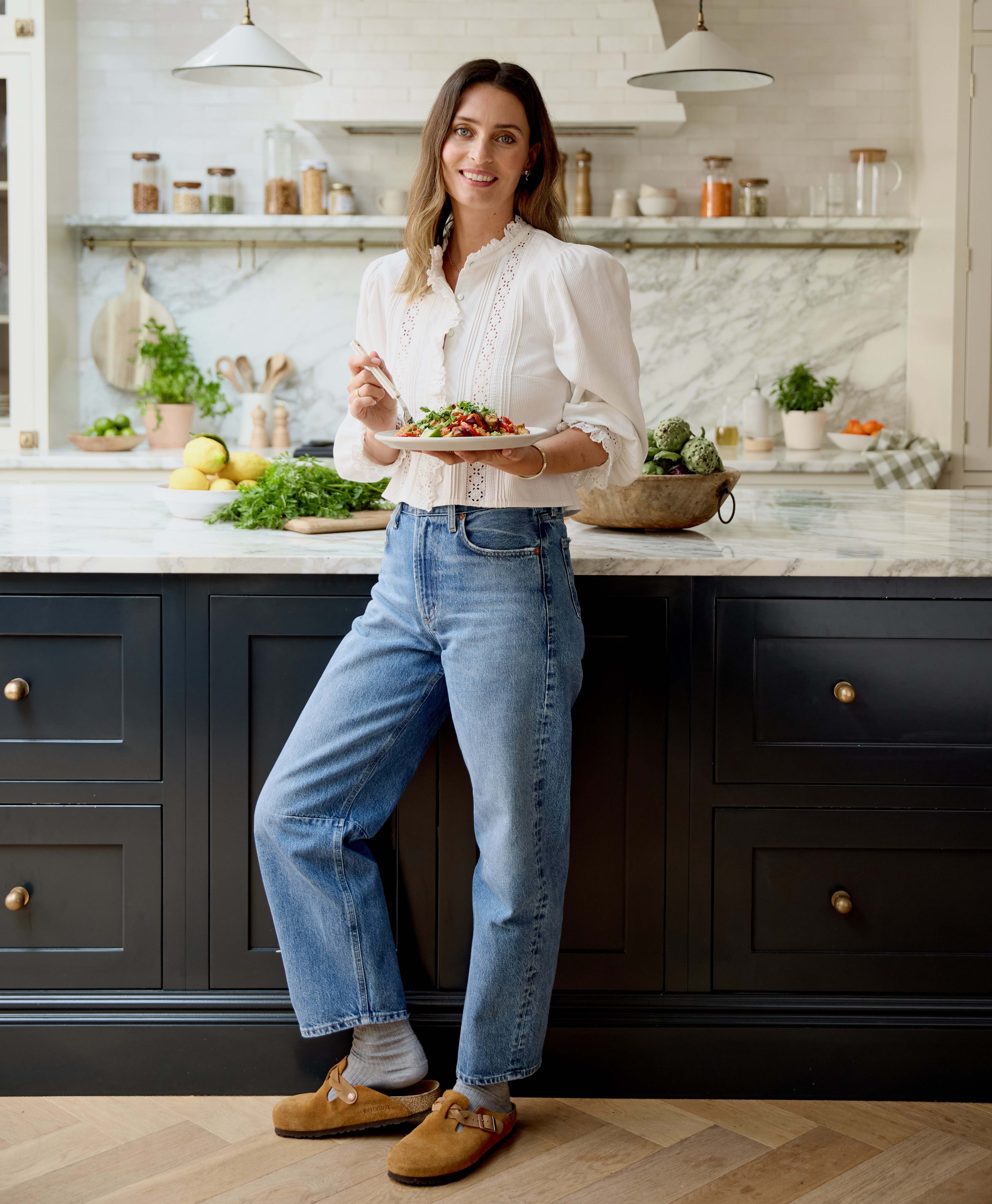 Ella Mills in her kitchen, holding a plate of food.
