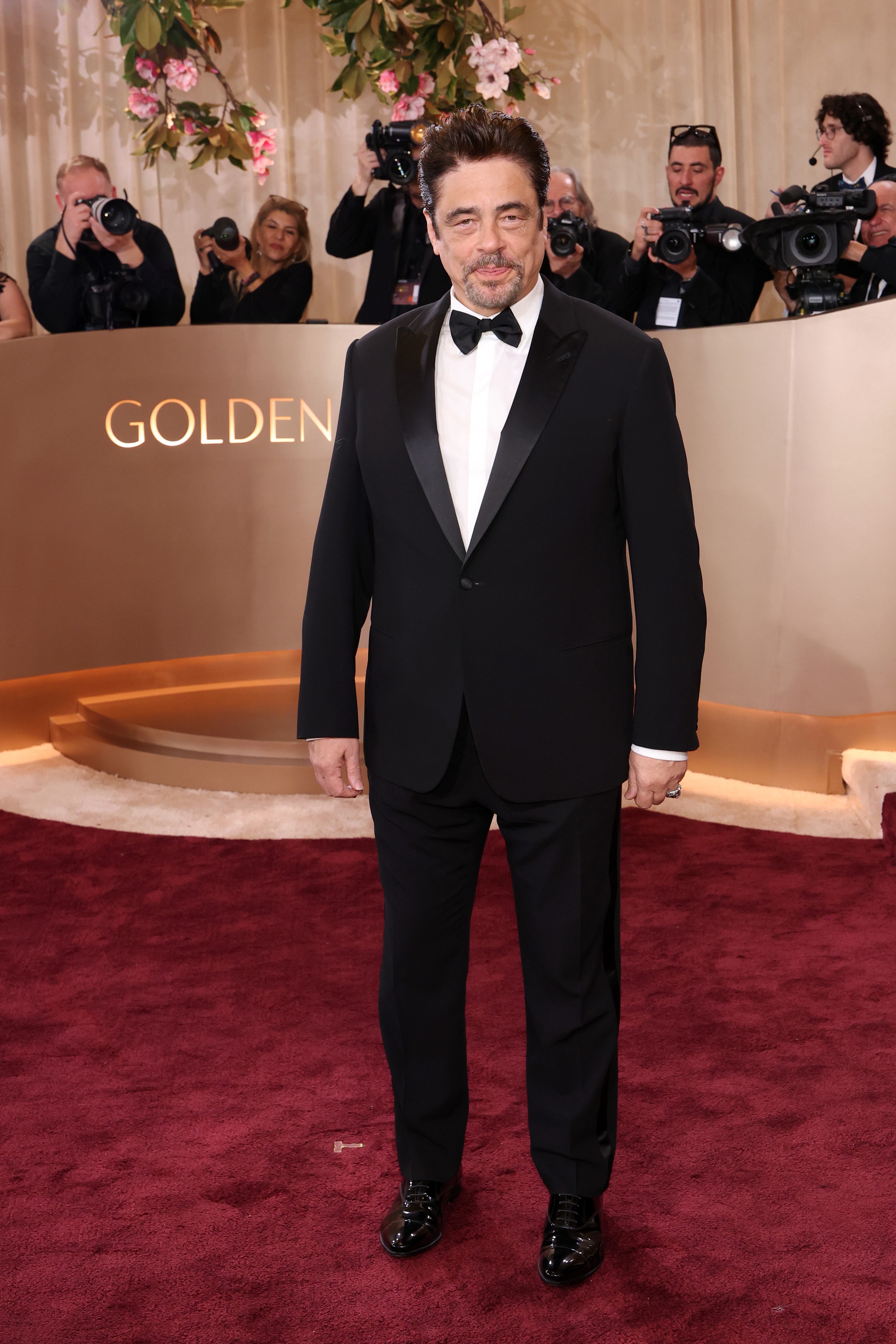 Benicio del Toro in a black tuxedo on the red carpet at the 83rd Annual Golden Globe Awards.
