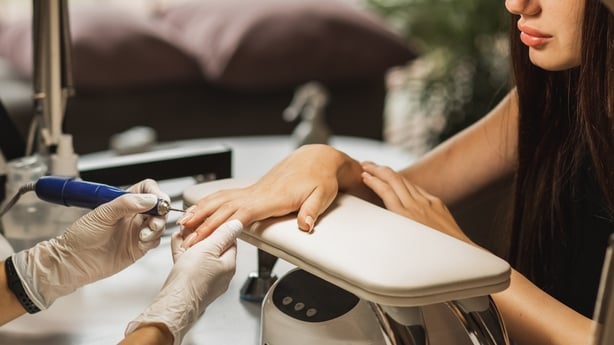Manicure master in gloves with cuticle remover device in beauty salon. Master using electric machine to remove the nail polish during manicure in the salon. Professional manicure tool. Concept of body care.