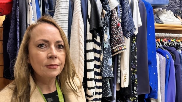 Collette Miller standing among clothes items donated to Barnardos