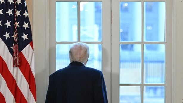 US President Donald Trump looks through a window to observe construction work on his new ballroom