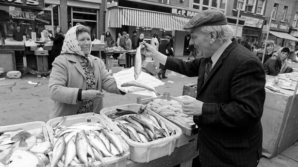 Irish actor/comedian Cecil Sheridan buys fish from trader May Gorman at her stall on Moore Street, Dublin city, on 26 February 1973. This shot was taken during a promotional shoot for an unidentified comedy show, although Sheridan was hosting a weekly half-hour programme of comedy and song, 'Hanniga