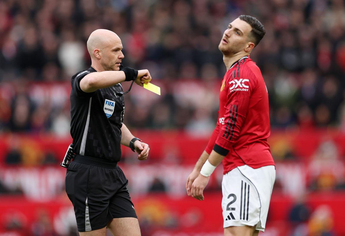 Anthony Taylor showing Diogo Dalot a yellow card
