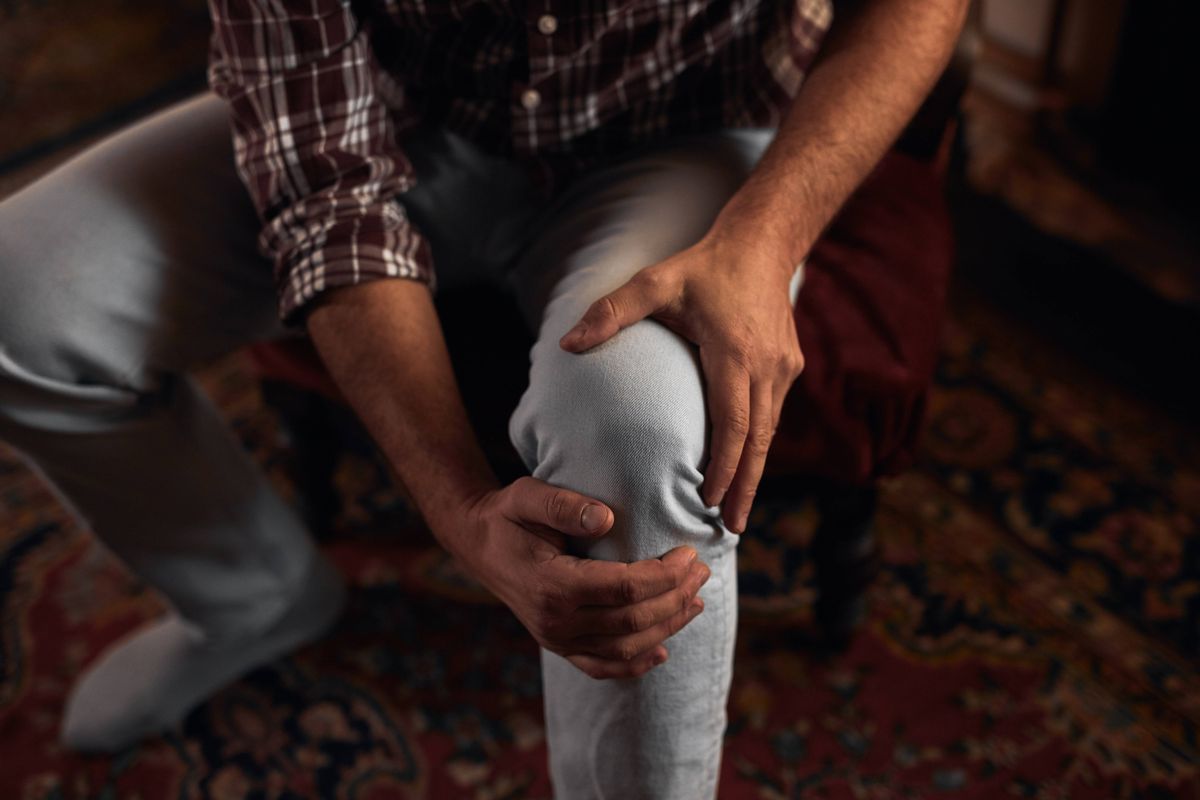 Man at home holding painful injured knee.