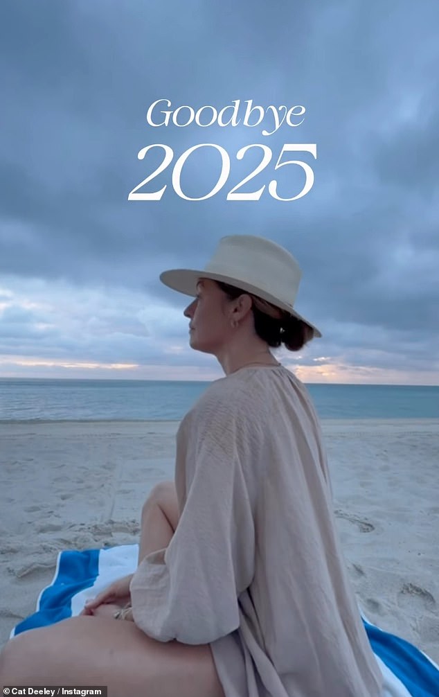 The beginning of the post showed Cat sat on a towel on a beach, wearing a beige cover-up and a fedora with the caption: 'Goodbye 2025'