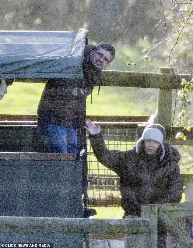 Cheryl wore a long brown puffer coat and sheepskin-lined, trapper-style hat with the ear flaps down