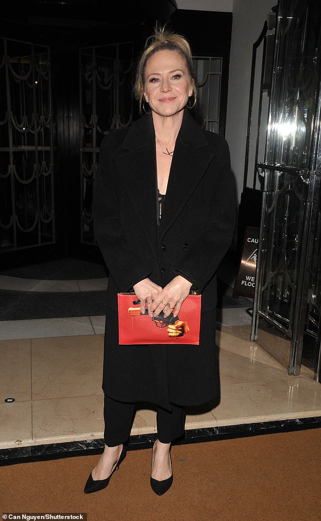 EastEnders star Kellie Bright wrapped up in a black coat which she wore over a low cut matching top and trousers