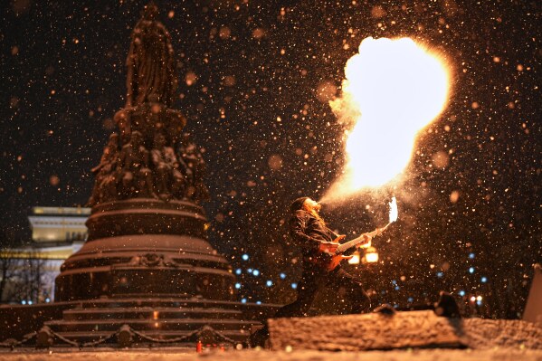 A street performer spits fire and plays a guitar in the snow in St. Petersburg, Russia, Dec. 29, 2025. (AP Photo/Dmitri Lovetsky, File)