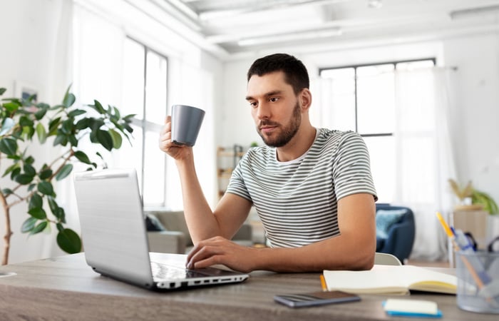 Investor sitting on front of a laptop at a desk.