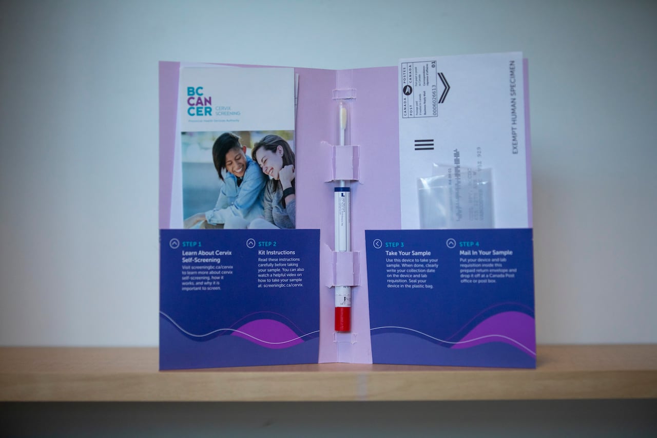 The inside of a blue and mauve folder, with a brochure in one pocket and an envelope in the other, and narrow plastic tube containing a swab affixed in the middle.