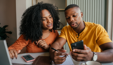 Couple discussing saving money and financial planning in front of a laptop with a calculator and notebook