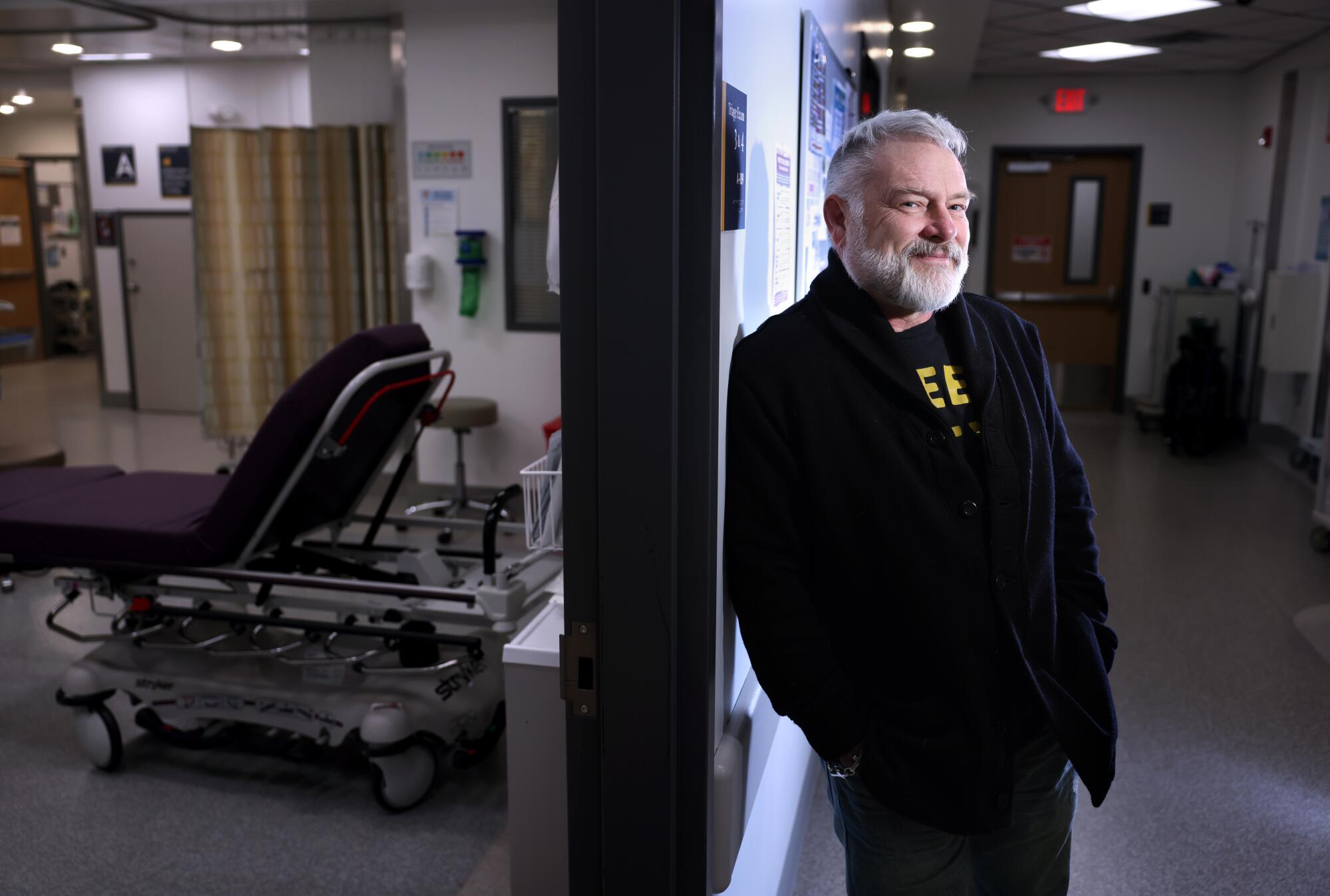 A man leans against a door frame inside a hospital