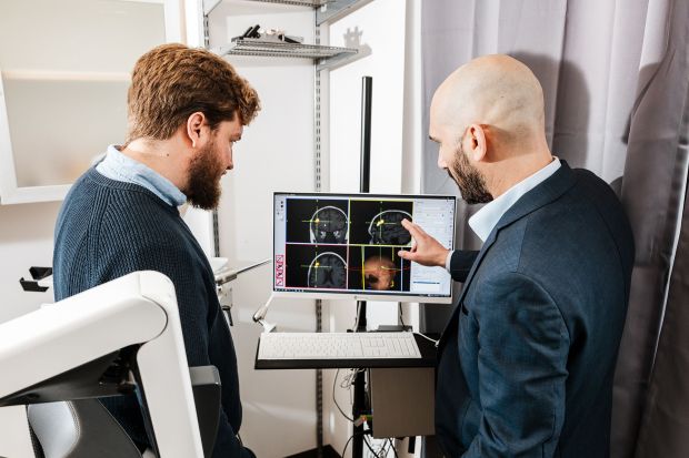 Dr. Christopher Austelle (left) and Dr. Ian Kratter examine Valerie Zeko's brain scans in a Brain Stimulation Lab treatment room.(Carolyn Fong for CNN via CNN Newsource)
