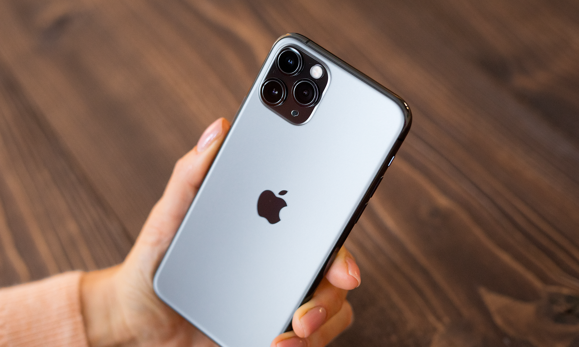 Person holding an iPhone with the Apple logo visible at the back.