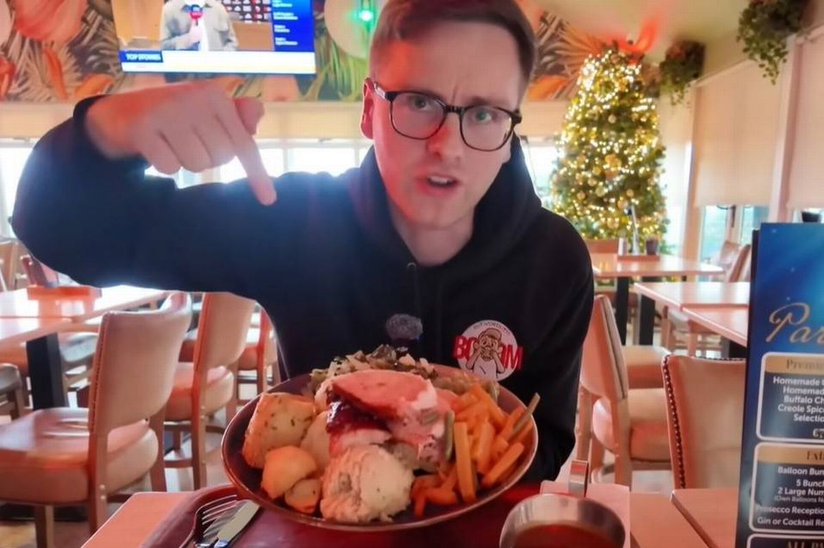 An individual seated at a table in a restaurant, holding a bowl filled with a variety of seafood, likely in the midst of dining.