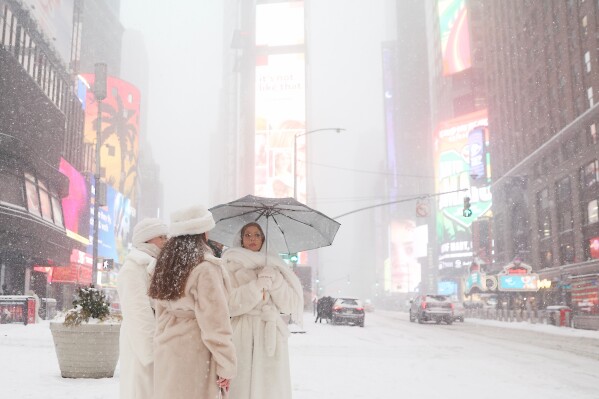 People wait to cross the street in Times Square during a winter storm, Sunday, Jan. 25, 2026, in New York. (AP Photo/Heather Khalifa, File)