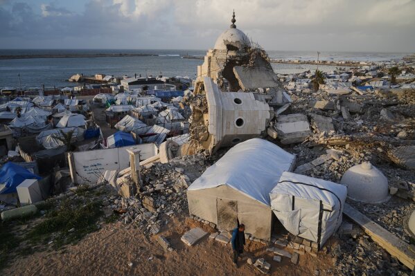 A man walks through tents sheltering displaced Palestinians amid the ruins left by the Israeli air and ground offensive in Gaza City, Wednesday, Jan. 28, 2026. (AP Photo/Jehad Alshrafi, File)