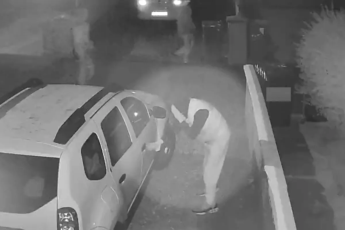 One of the men covered his face with his hand as he checked if a car was locked