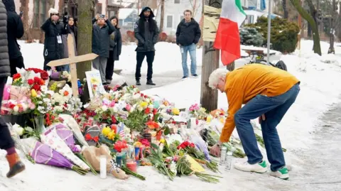 Eloise Alanna/BBC A man leaves flowers at a vigil 