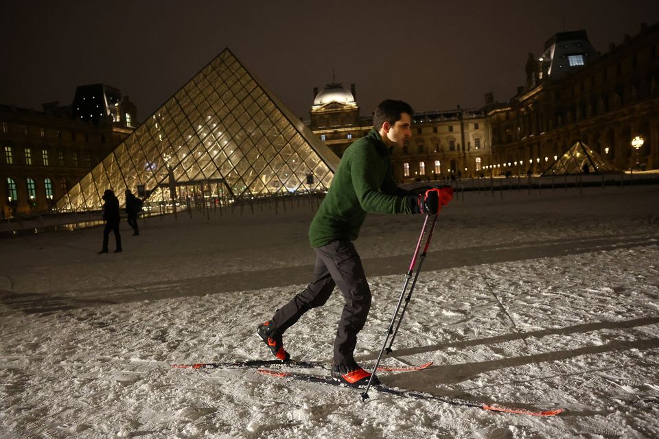 A man skis on the snow-covered courtyard in front of the glass Pyramid of the Louvre Museum in Paris. REUTERS/Abdul Saboor