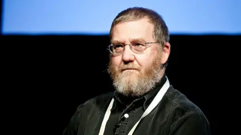 Teradata Bearded, Professor Mark Whitehorn, wears a black denim shirt.