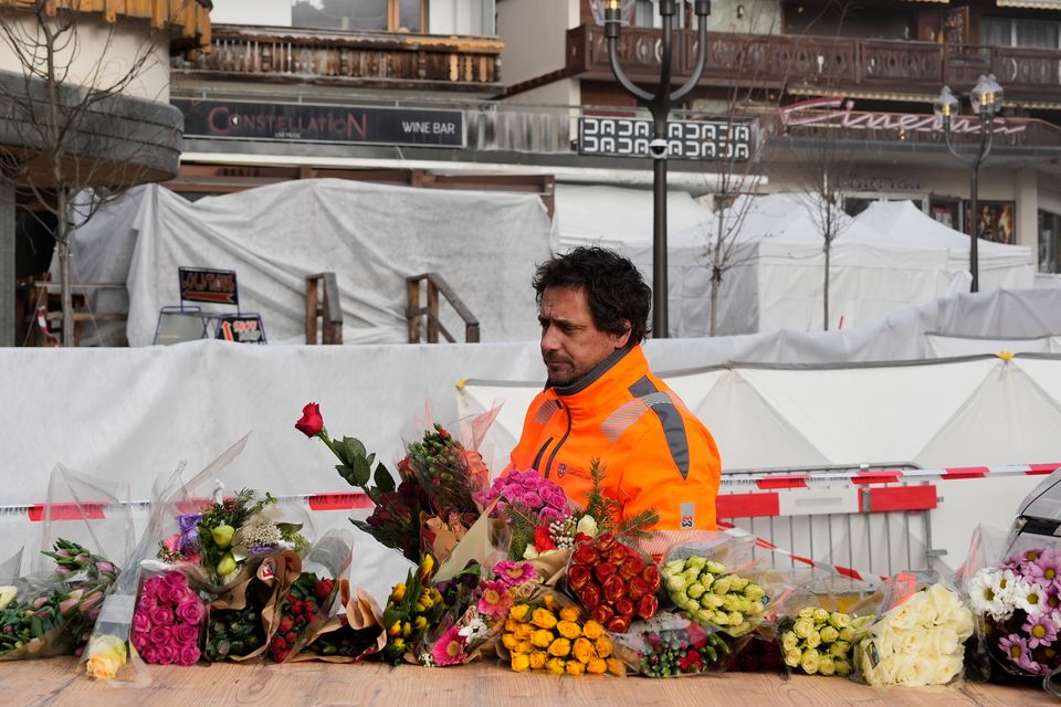 Municipal workers move flowers closer to the sealed off Le Constellation bar in Crans-Montana, Swiss Alps, Switzerland, where a devastating fire left dead and injured during the new year’s celebrations (Baz Ratner/AP)